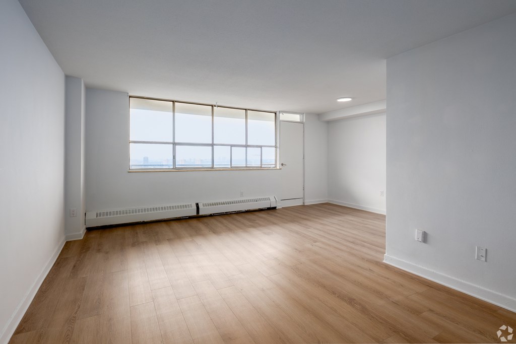 A room with wooden flooring and a window with a view of the outside.
