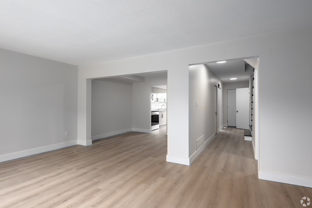 A spacious room with wooden flooring and white walls.