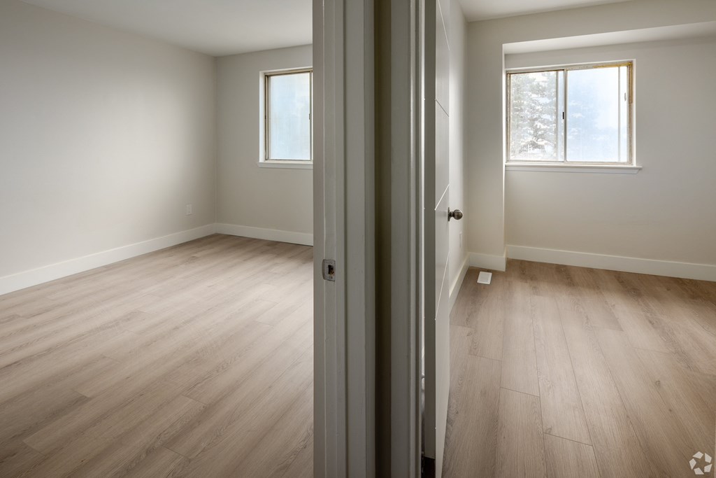 A room with wooden flooring and a window with a view of snow outside.