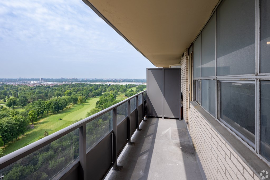 A balcony with a view of a green landscape and a distant city skyline.