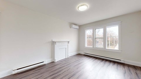 A room with a window, a radiator, and a white fireplace.