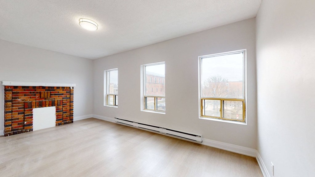 A room with a fireplace and three windows.