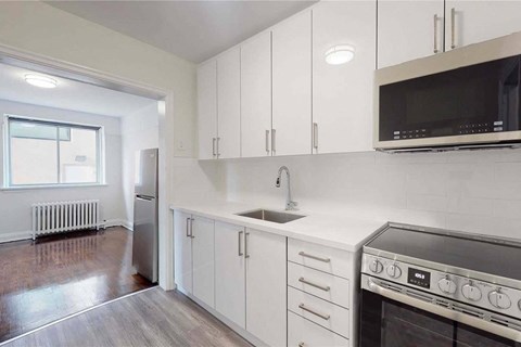 A kitchen with white cabinets and a black microwave.