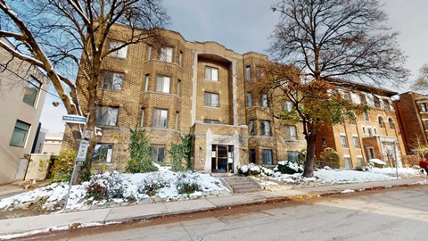 A large brick building with a tree in front of it.