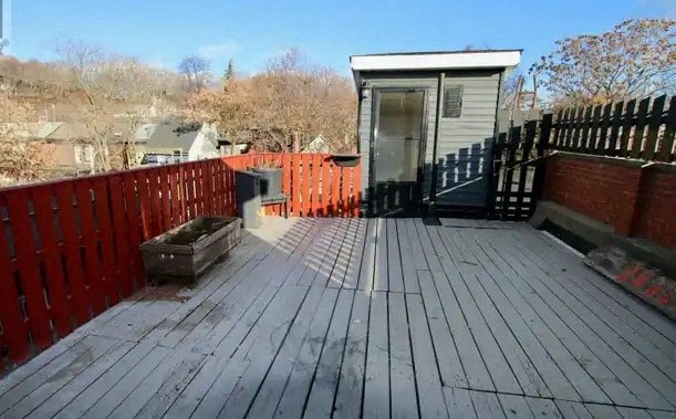 A wooden deck with a small building and a black fence.