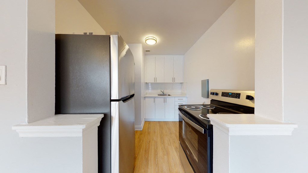 A kitchen with a black refrigerator and a white oven.