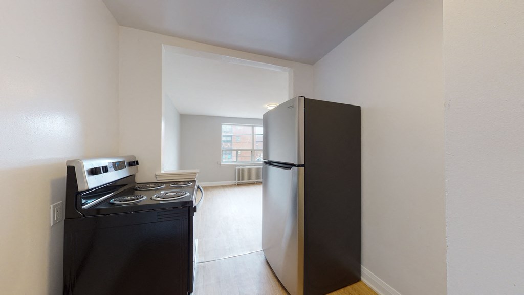 A black fridge and stove in a small kitchen.