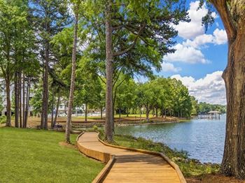 A wooden walkway runs along the edge of a lake, bordered by trees.