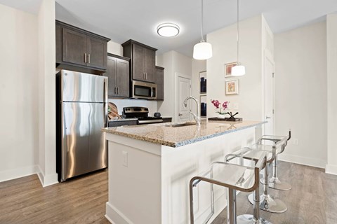 A kitchen with a granite counter top and stainless steel appliances.