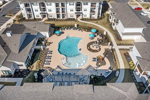 An aerial view of a resort with a swimming pool and a parking lot.