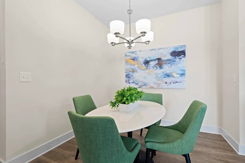 A dining room with a white table and green chairs.