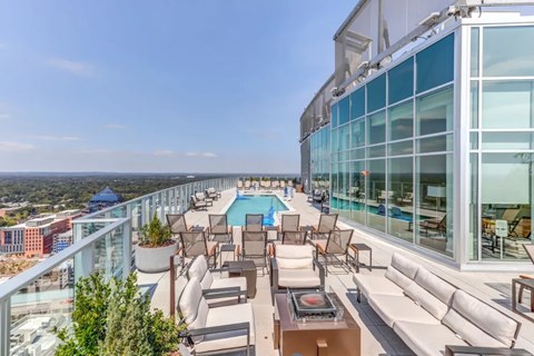 A rooftop patio with a pool and chairs.