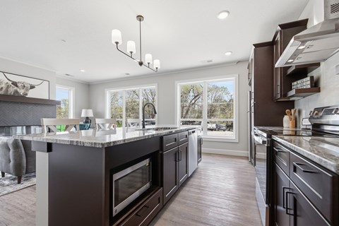 A modern kitchen with dark wood cabinets and a marble countertop.