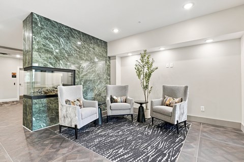 A living room with a green marble wall and white chairs.