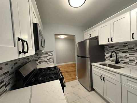 A kitchen with white cabinets and a black stove top.