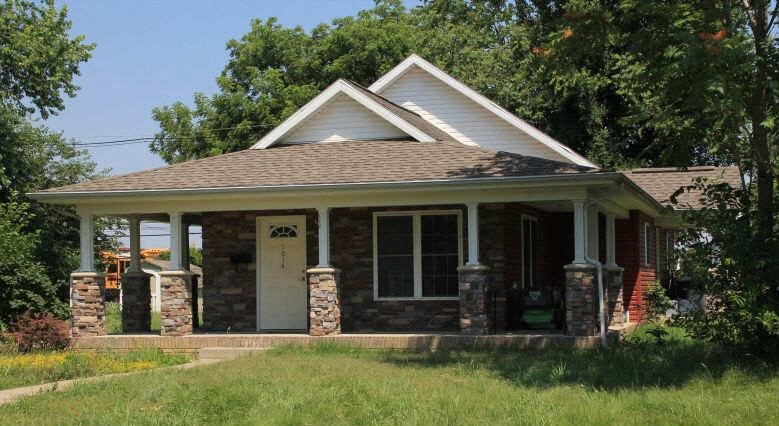 a small brick house with a porch and a door