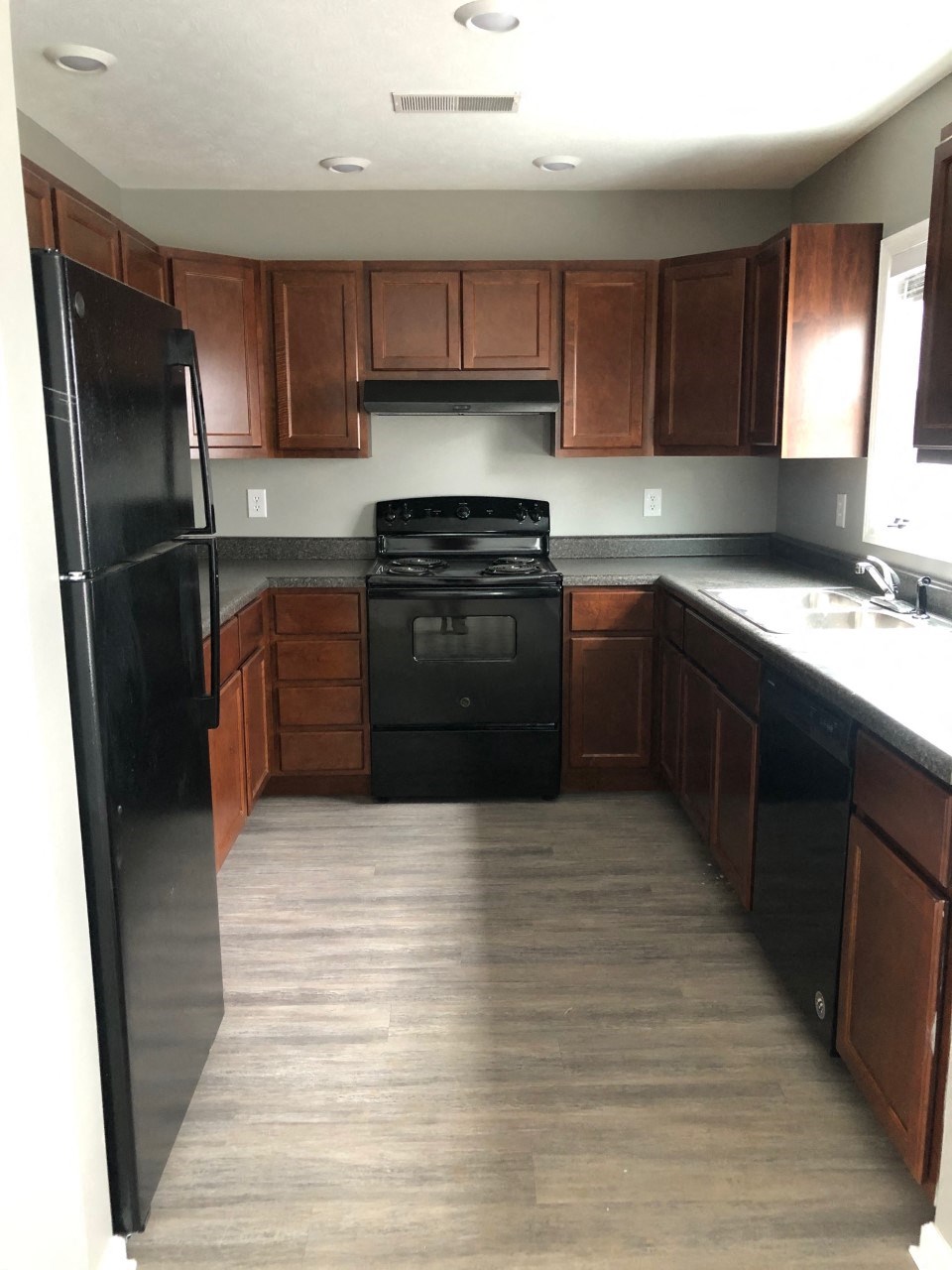 an empty kitchen with black appliances and wooden cabinets
