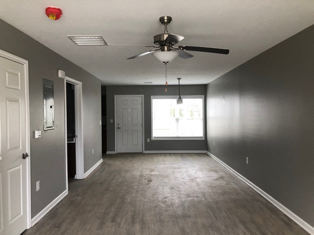 an empty living room with a ceiling fan and a window