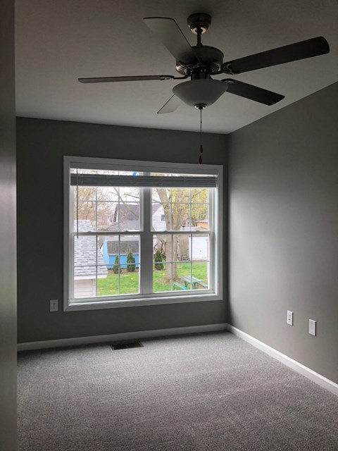 a living room with a large window and a ceiling fan