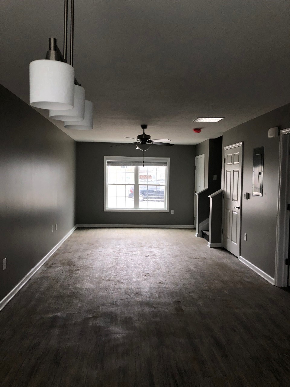 an empty living room with gray walls and a window