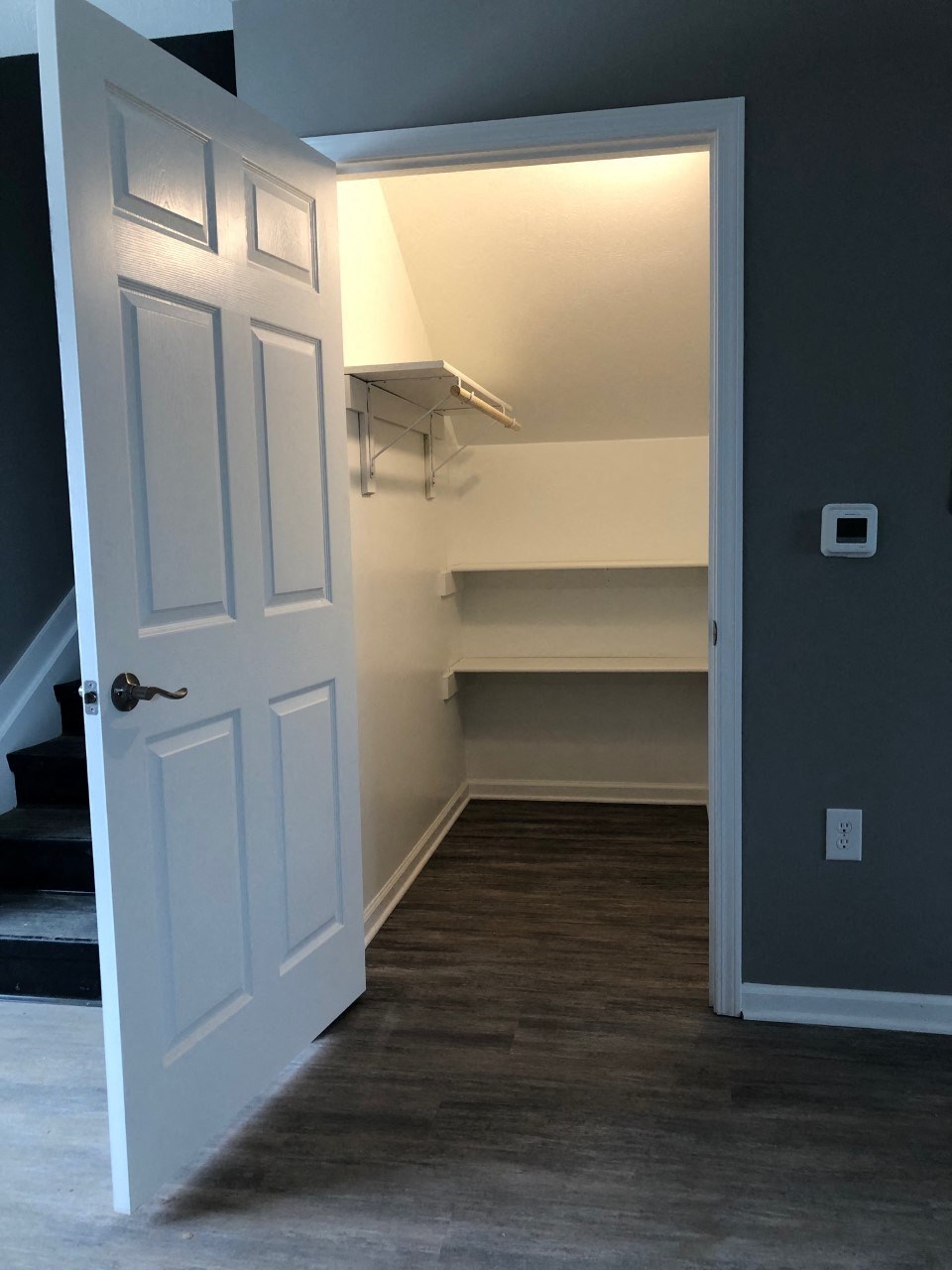 a walk in closet with a white door and a stairwell