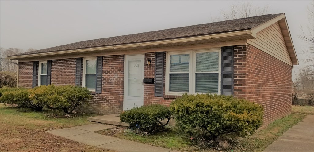a small brick house with a sidewalk in front of it
