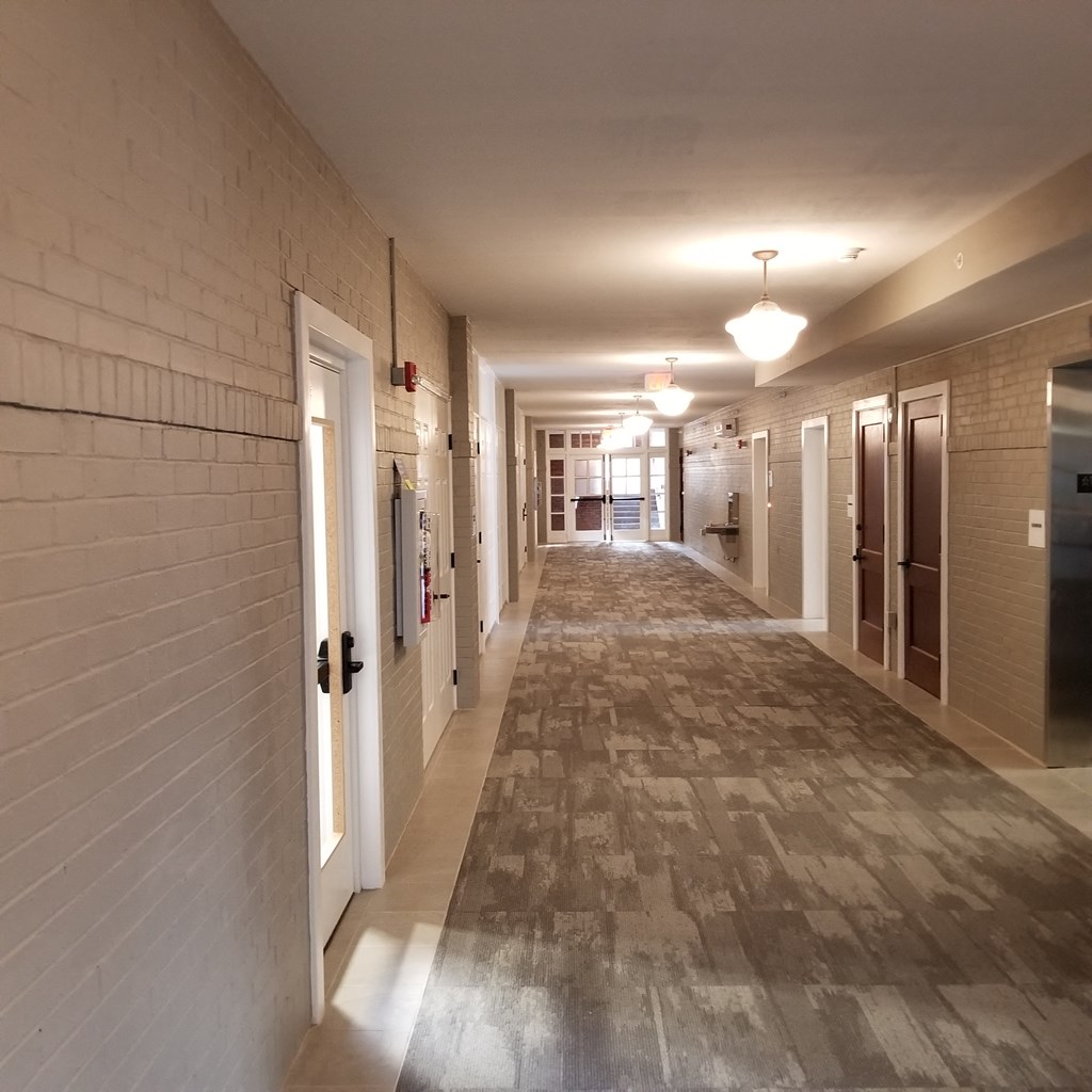 a hallway with white brick walls and doors and a tile floor