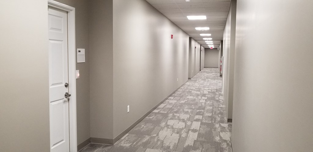 a hallway in a building with white walls and a tiled floor