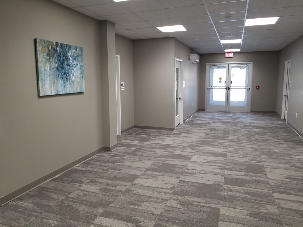 an empty hallway with a painting on the wall and a door in the end