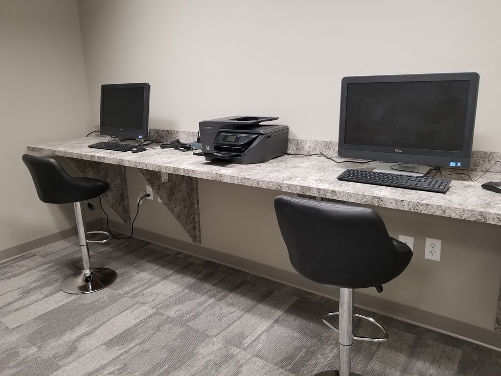 a desk with two computers and a printer on it