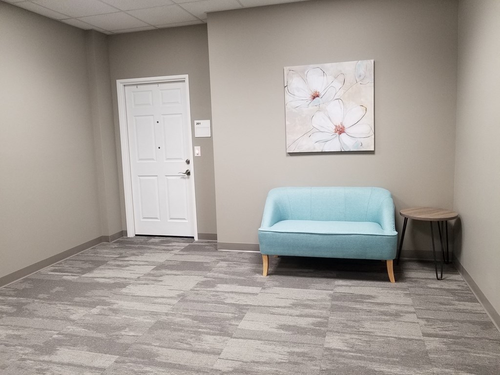 a room with a blue chair and a painting on the wall