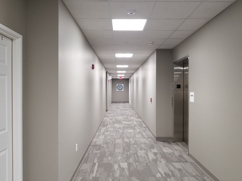 an empty hallway in a building with white and gray walls and white doors and ceilings
