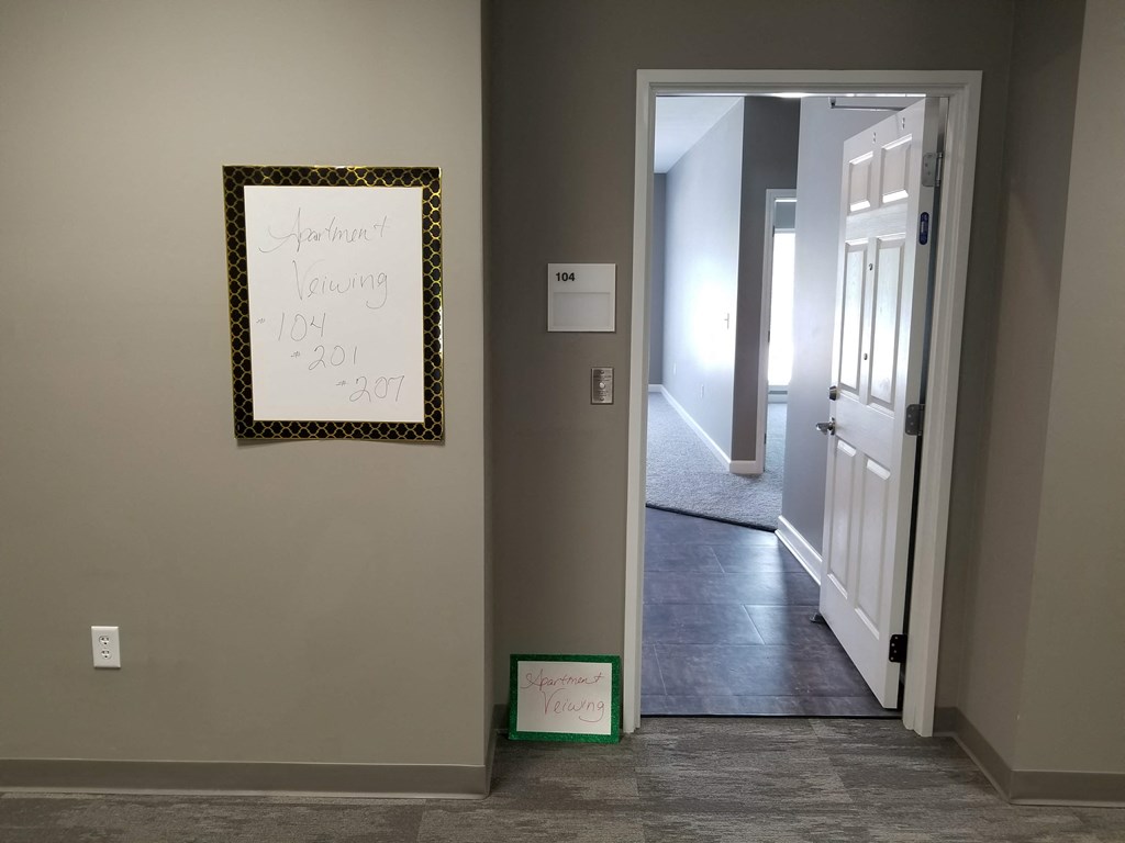 a hallway with a white door and a mirror on the wall and a door open