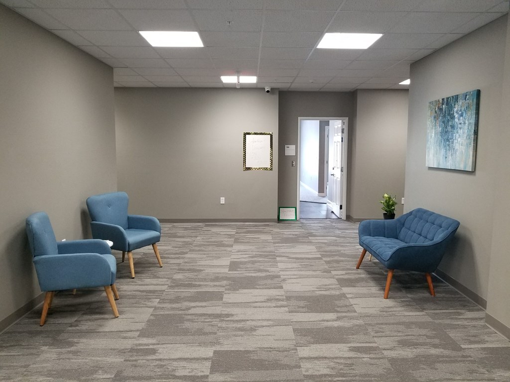 a waiting room with blue chairs and a wall with a door