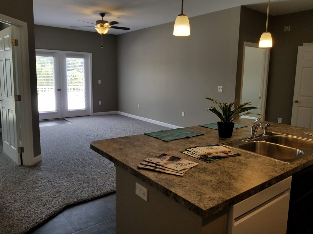 an empty kitchen and living room with a sink and a ceiling fan