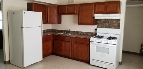 an empty kitchen with white appliances and wooden cabinets