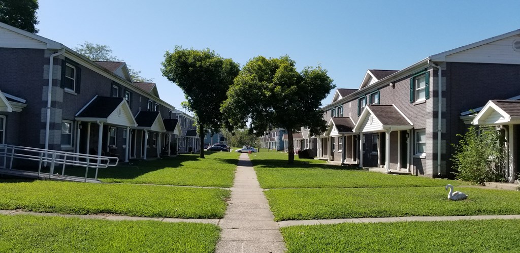 a row of houses down a sidewalk with grass and trees