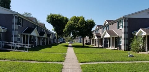 a row of houses down a sidewalk with grass and trees