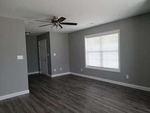 an empty living room with a ceiling fan and a window