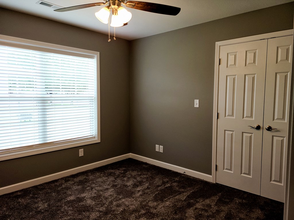 a bedroom with a ceiling fan and a window and a door