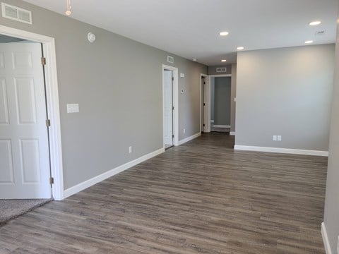 a living room with a wood floor and grey walls and white doors