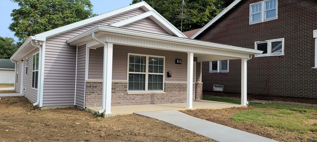 the front of a house with a porch and a sidewalk