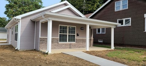 the front of a house with a porch and a sidewalk