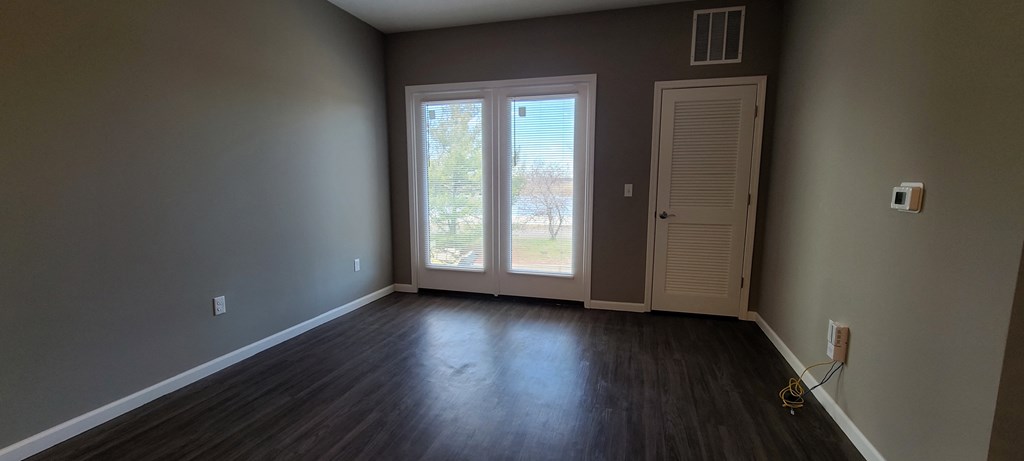 an empty living room with wood floors and a door and window