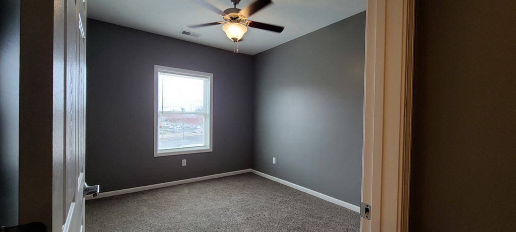 an empty room with a ceiling fan and a window