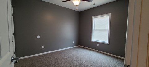 an empty room with a ceiling fan and a window