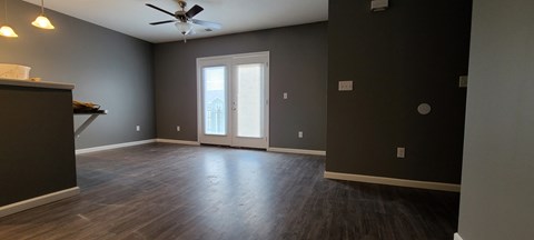 an empty living room with wood floors and a ceiling fan