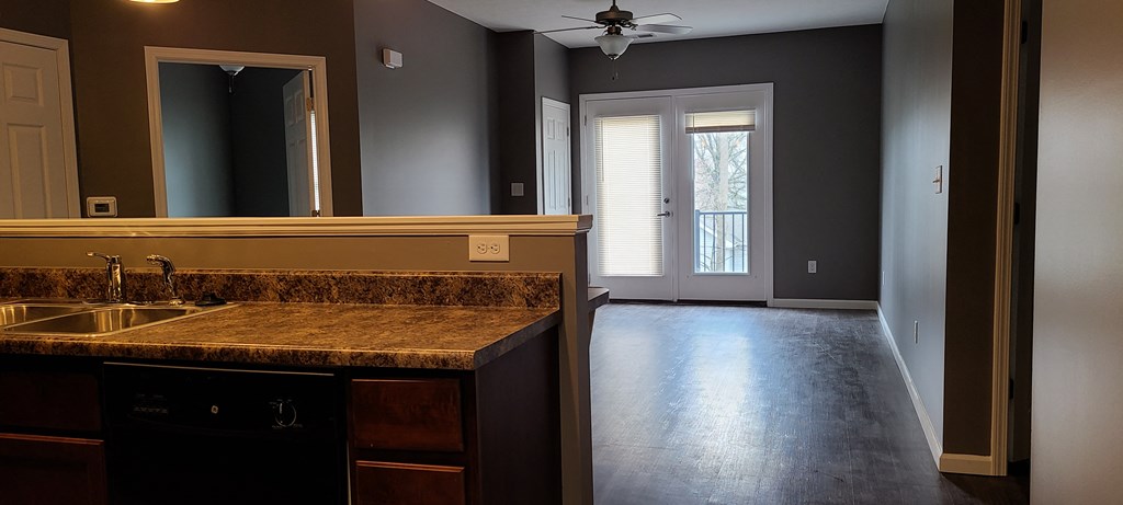 an empty kitchen and living room with a sink and a ceiling fan