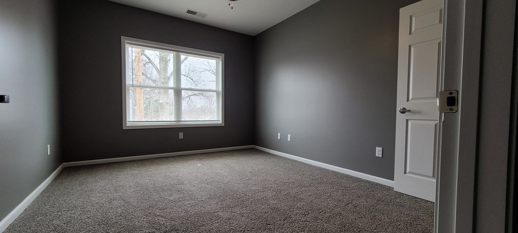 an empty room with gray walls and a window