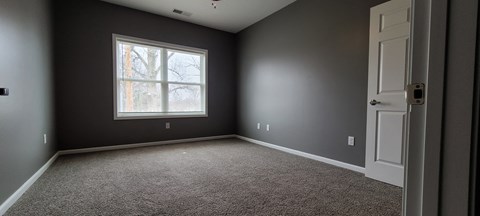 an empty room with gray walls and a window